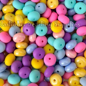 May include: A close-up shot of a pile of colorful beads in various shapes. The beads are in shades of yellow, pink, purple, blue, and green. The text "Gladiolus Beading Supplies" is visible at the bottom.