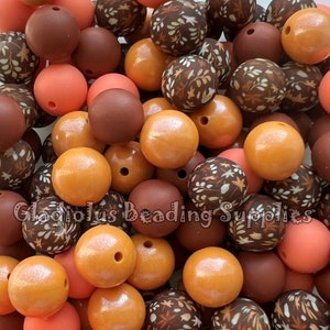 May include: A collection of wooden beads in various colors and patterns, including brown, orange, and peach. Some beads have a floral design, while others are solid.