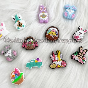 May include: A collection of 12 colorful Easter-themed shoe charms featuring bunnies, gnomes, baskets of eggs, and a truck with eggs. The charms are made of silicone and are perfect for adding a festive touch to your shoes.