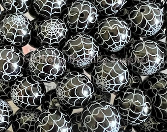 May include: A large group of black and white round beads with a spiderweb design. The beads are glossy and have a smooth surface.