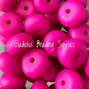May include: A close-up image of a pile of bright pink silicone beads. The beads are round and have a hole in the center. The beads are perfect for making necklaces, bracelets, and other jewelry.