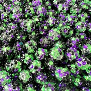 May include: Close-up of a large quantity of small, round, iridescent beads. The beads are a mix of black, green, and purple.