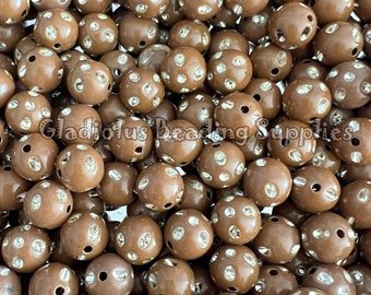 May include: A close-up of a pile of brown round beads with clear rhinestones. The beads have two holes for stringing.