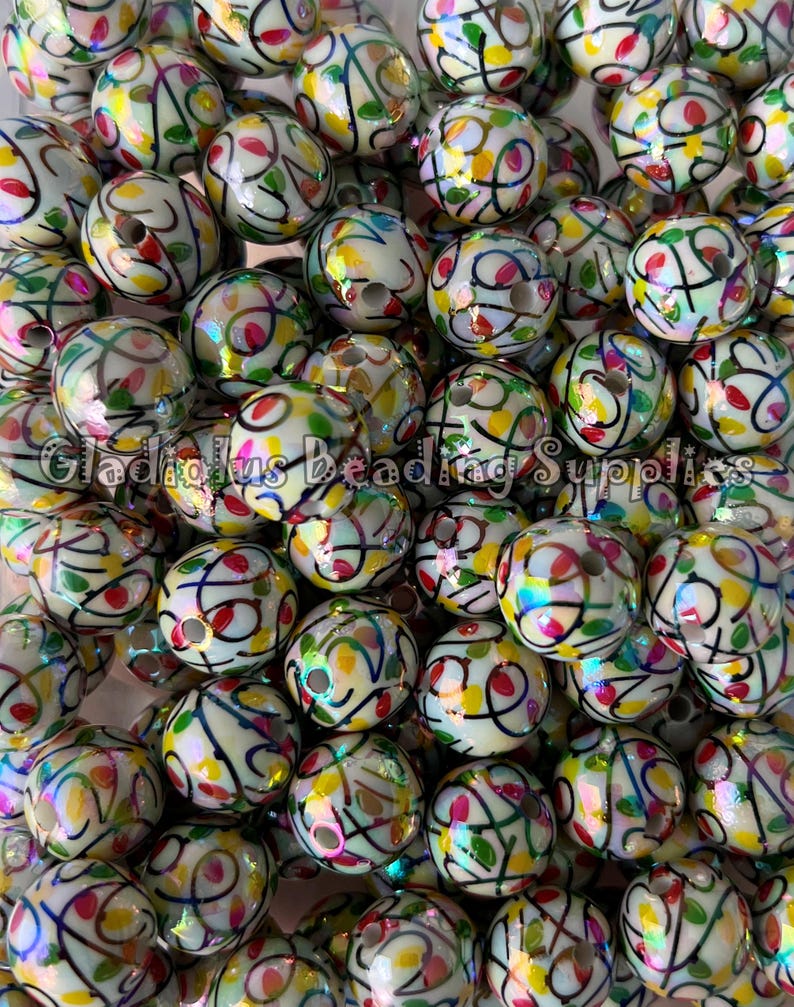 Puede incluir: Un conjunto de cuentas redondas, blanquecinas, con dise&ntilde;os abstractos coloridos. Las cuentas presentan un patr&oacute;n de l&iacute;neas negras y acentos coloridos en rojo, amarillo y verde. El texto "Gladious Beading Supplies" es visible.