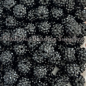 May include: A close-up of a pile of black rhinestone beads. The beads are round and have a sparkly finish. They are perfect for jewelry making or other craft projects.