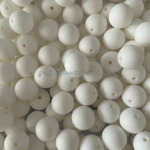 May include: A close-up image of a large quantity of white silicone beads. The beads are round and have a matte finish.