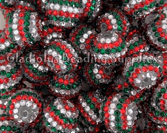 May include: Close-up of a pile of round beads. The beads are silver with red, green, and white rhinestones. The text "Gladious Beading Supplies" is visible at the bottom of the image.