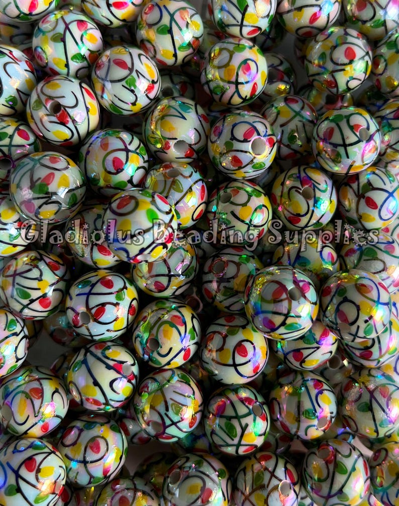 Puede incluir: Un conjunto de cuentas redondas con una base color crema, adornadas con dise&ntilde;os abstractos coloridos en rojo, amarillo, verde y negro. Las cuentas tienen un acabado brillante y un agujero para ensartar. El texto "Gladiolus Beading Supplies" es visible.