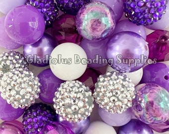 May include: A collection of purple, white, and silver beads. The beads are various shapes and sizes, including round, faceted, and sparkly. The beads are perfect for making jewelry or other crafts.
