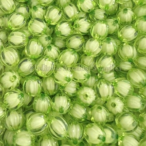 May include: A large pile of light green plastic beads with a white center. The beads are oval shaped and have a ribbed texture.