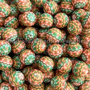 May include: A large pile of colorful, patterned wooden beads. The beads are round and have a geometric design in shades of orange, green, and white.