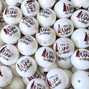 May include: A close-up of a pile of white round beads with the text "It's Wine o'clock" printed in brown on each bead.