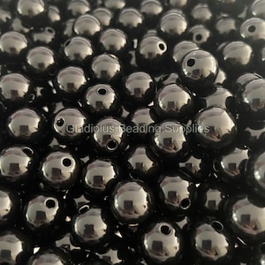 May include: A large quantity of black round beads. The beads are smooth and shiny, and they have a small hole in the center.