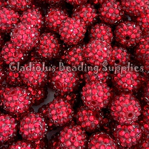 May include: A close-up image of a pile of red rhinestone beads. The beads are round and have a sparkly finish. The beads are ideal for jewellery making, crafts, and other projects.