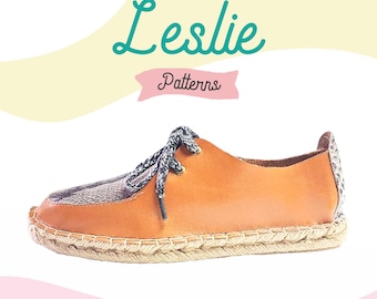 May include: A brown leather espadrille shoe with a black and white patterned toe. The shoe has a rope sole and laces. The text "Leslie Patterns" is visible in the image.