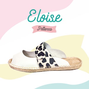 May include: White leather espadrille sandal with a black and white cow print strap. The sandal has a woven jute sole and the text "Eloise Patterns" in teal and pink.