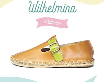 May include: A tan leather espadrille shoe with a green strap and buckle. The shoe has a woven sole and is labeled "Wilhelmina Patterns". The design features a classic, casual style.