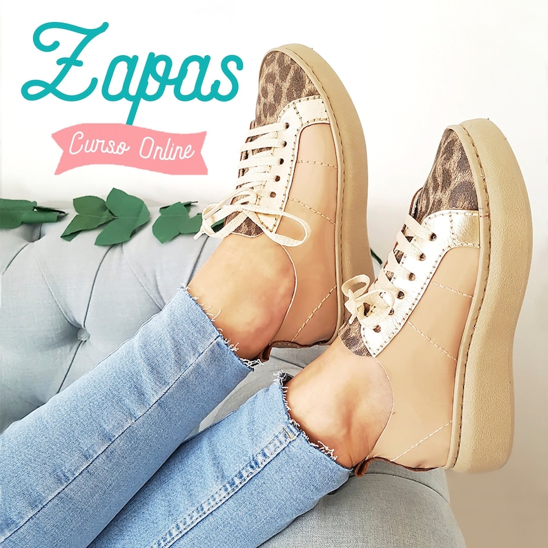 May include: A pair of beige canvas sneakers with gold accents and a leopard print detail. The sneakers are worn by a person wearing blue jeans.