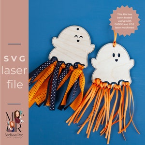 Könnte beinhalten: Zwei unfertige Holz-Geister-Anhänger mit lächelnden Gesichtern. Jeder Geist hat einen Fransen aus orangem und schwarzem Band, der an der Unterseite befestigt ist.