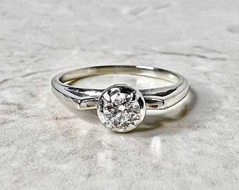 Könnte beinhalten: Ein schlichter Silber-Verlobungsring mit einem einzelnen runden Diamanten.