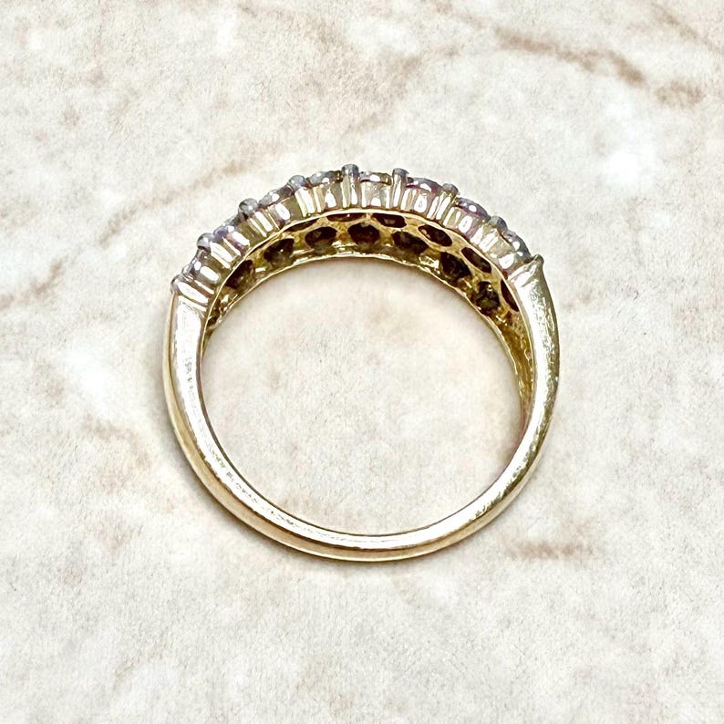 May include: A gold band ring with a row of small, clear stones set in a channel setting.