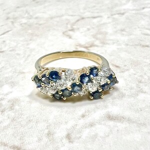 May include: A gold band ring with a cluster of blue sapphires and white diamonds set in a wave-like pattern.