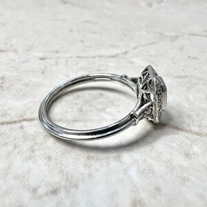 Puede incluir: Un anillo de plata con una piedra central de forma cuadrada rodeada por un delicado dise&ntilde;o de filigrana.