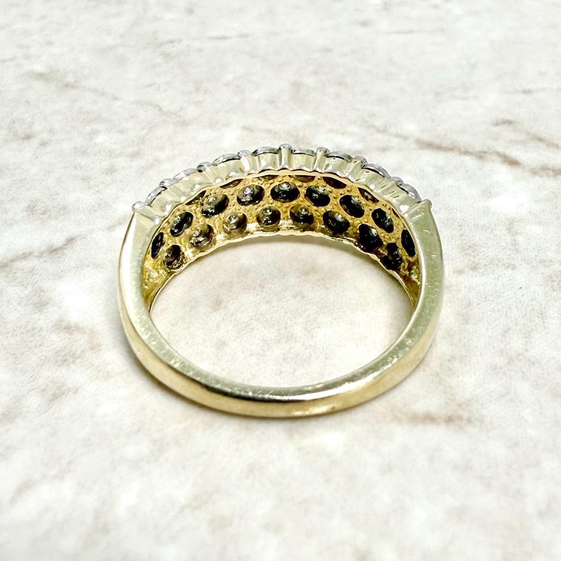 May include: A gold band ring with a row of small, round, clear stones set in a channel setting.