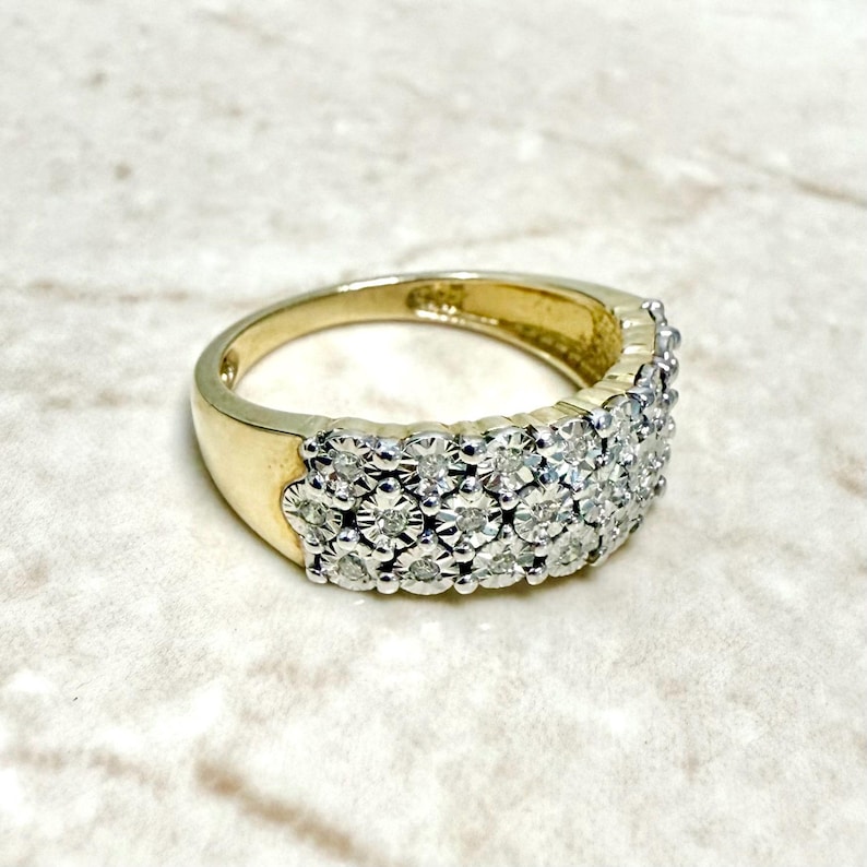 May include: A gold band ring with a row of small, clear diamonds set in a pave setting.