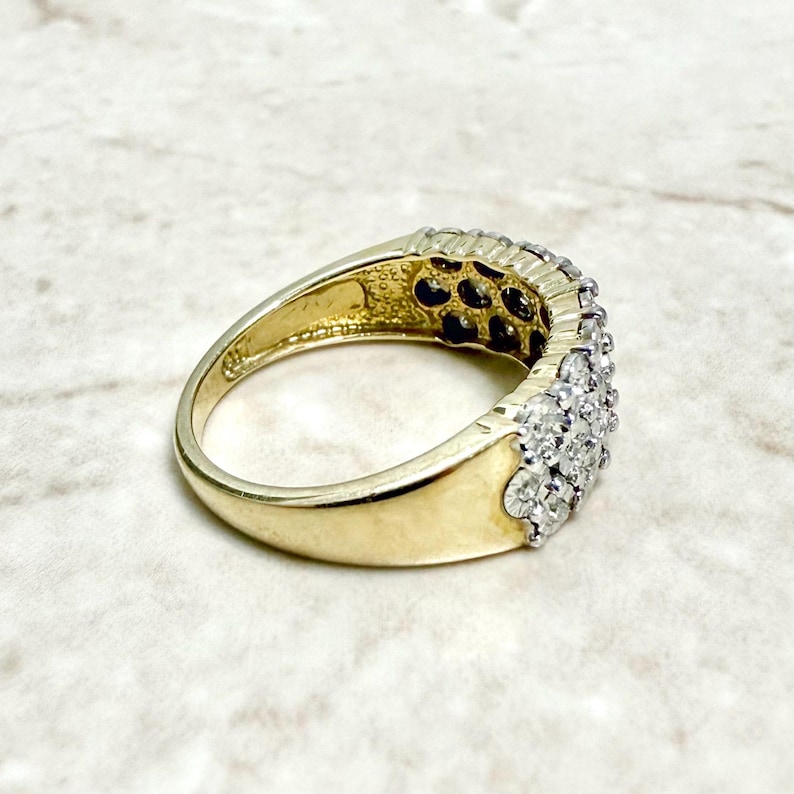 May include: A gold band ring with a row of small, clear diamonds set in a pave setting.