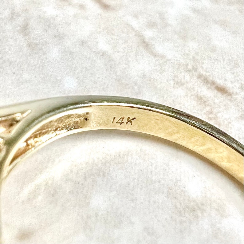 May include: Close-up of the inside of a gold ring with the inscription "14K" on the band.