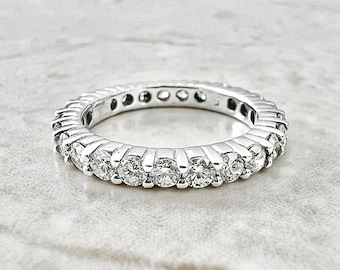 May include: A silver band with a row of round, clear diamonds set in a smooth, continuous line.
