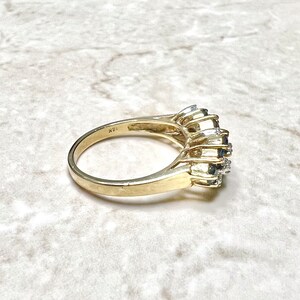 May include: A gold band ring with a cluster of blue sapphires and diamonds. The ring is marked "14K" on the inside of the band.