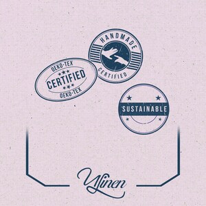 Op de afbeelding: Lichtroze achtergrond met drie marineblauwe stempels. De stempels tonen de tekst "OEKO-TEX CERTIFIED", "HANDMADE CERTIFIED" en "SUSTAINABLE". Het woord "Ylinen" staat onderaan in cursief.