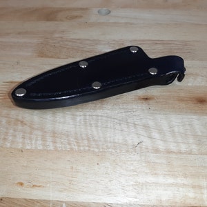 May include: Black leather knife sheath with silver rivets.