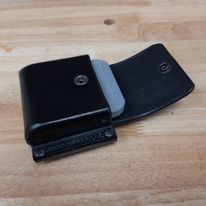 May include: A black leather case with a snap closure and a gray insert. The case is open and the insert is visible.