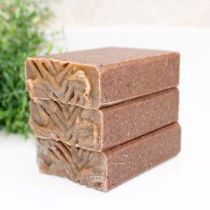 May include: A stack of three brown and beige soap bars with a textured surface. The soap bars are stacked on top of each other.