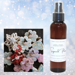 May include: A brown glass bottle with a black spray nozzle. The bottle is labeled "Baba Yaga Designs Linen + Room Scented Spray Sugared Plums Sugared plums + white musk + mulled citrus Add a touch of magic to your home Net Wt 4 oz / 118.3 g"