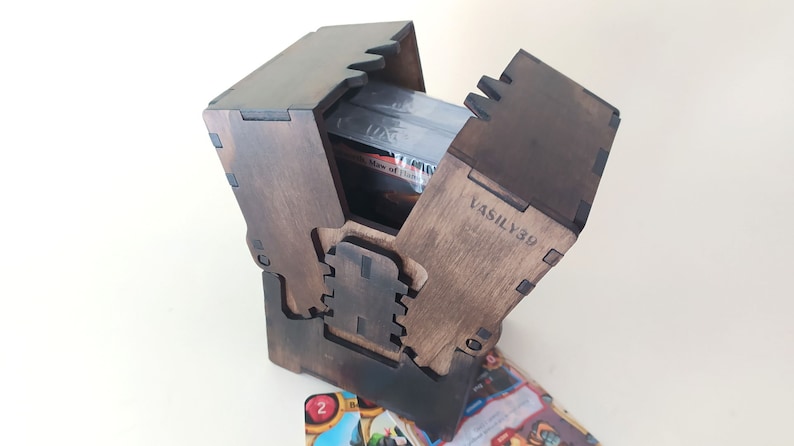 May include: A wooden card box with a hinged lid, open to reveal a stack of cards. The box is decorated with a carved design and the inscription "VASILY39".