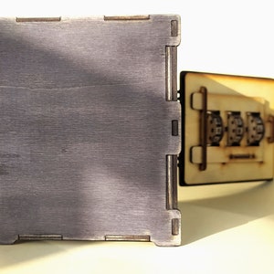 May include: A wooden box with a combination lock. The box is made of light brown wood and has a dark brown finish. The combination lock has three dials with numbers on them.