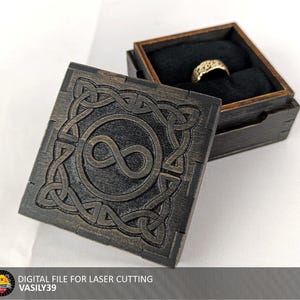 May include: A white ceramic mug with a black handle and the text "But First, Coffee" in a bold, black font. The mug is set against a blurred background, suggesting a cozy setting.