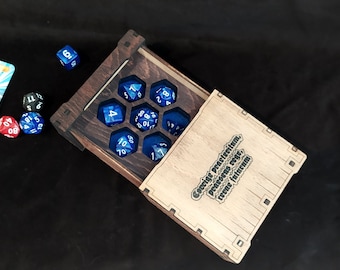 May include: A wooden dice box with a hinged lid, open to reveal blue dice with white numbers. The box has a dark wood stain and a laser-engraved inscription on the lid that reads "Gaming, procrastination, procrastinating, gaming, repeat infinitum".