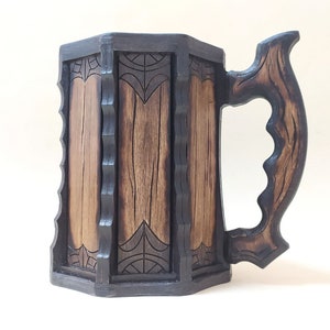 May include: A wooden beer stein with a dark brown finish and intricate carvings. The handle is shaped like a branch and has a textured surface.