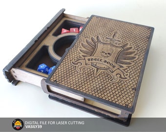Puede incluir: Una caja de madera con forma de libro con un diseño de calavera y alas en la portada. La caja está abierta y tiene un compartimento para dados y una taza pequeña. La caja está etiquetada como "Spell Book".