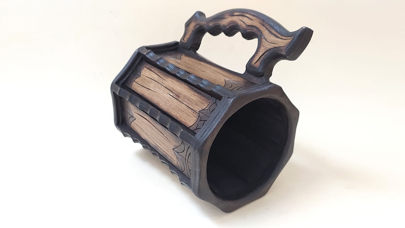 May include: A wooden beer stein with a dark brown finish and a carved wooden handle. The stein has a hexagonal shape and is decorated with a wood grain pattern.