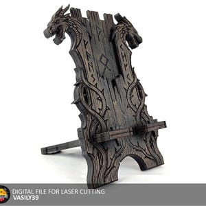 Puede incluir: Un soporte de madera marrón oscuro para teléfono o tableta con tallas de cabeza de dragón. El soporte tiene un diseño decorativo con runas y enredaderas. La base está en ángulo para una visualización óptima. El texto "DIGITAL FILE FOR LASER CUTTING" está en la parte inferior.