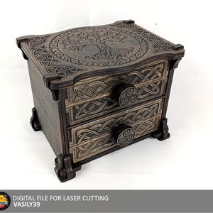 May include: A dark brown wooden chest with two drawers, featuring intricate laser-cut Celtic knotwork patterns on the drawer fronts and a detailed tree design on the top surface. Each drawer is equipped with a circular knob featuring a triskelion.