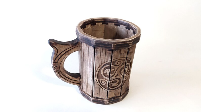 May include: A wooden mug with a Celtic knot design. The mug is brown and has a handle.