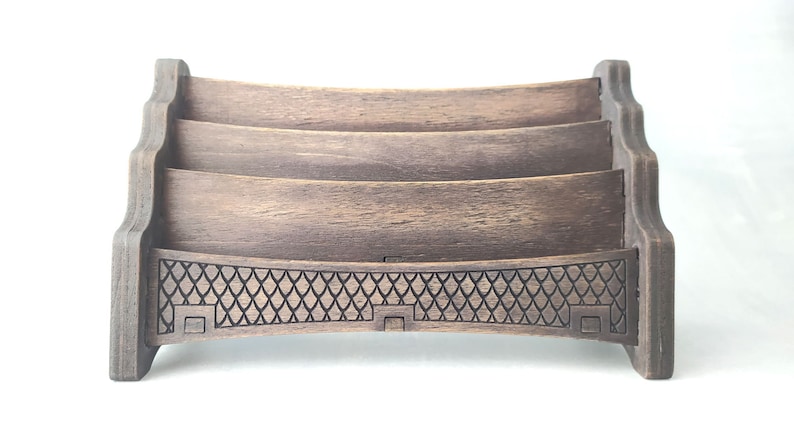 May include: A wooden letter holder with three tiers and a decorative bottom. The holder is dark brown and has a distressed finish.