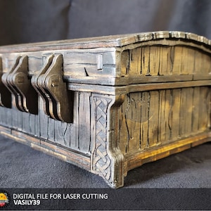 May include: A wooden box with a hinged lid and a intricate latch mechanism. The box is made of dark wood with a distressed finish and has a Celtic knot design on the side.